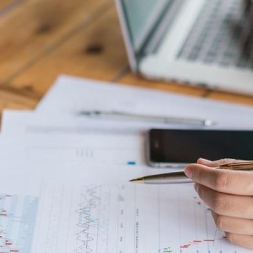 Business woman hand with Financial charts and laptop on the table